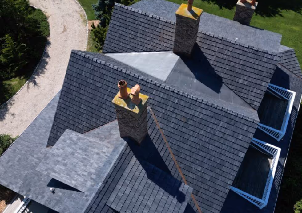 Aerial view of a roof featuring multiple chimneys against a clear blue sky.
