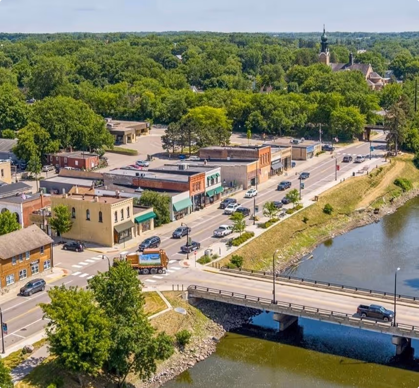 Aerial view of a small town featuring a winding river and a bridge connecting both sides of the landscape.