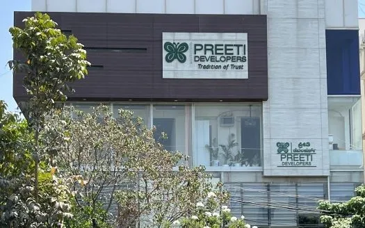 Modern building facade with two Preeti Developers signs and trees in the foreground.