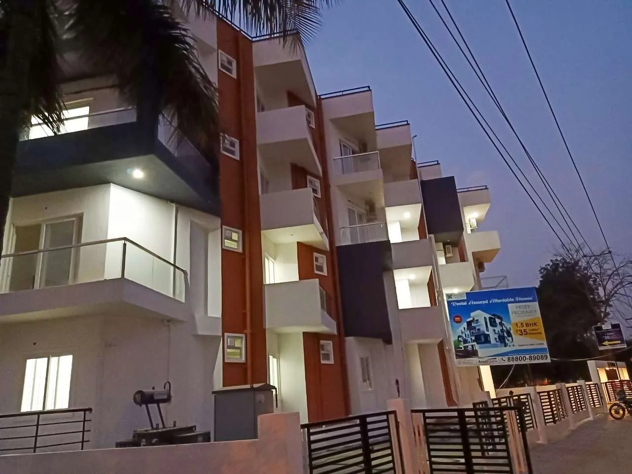 Evening view of a modern multi-storey apartment building with balconies and illuminated windows.