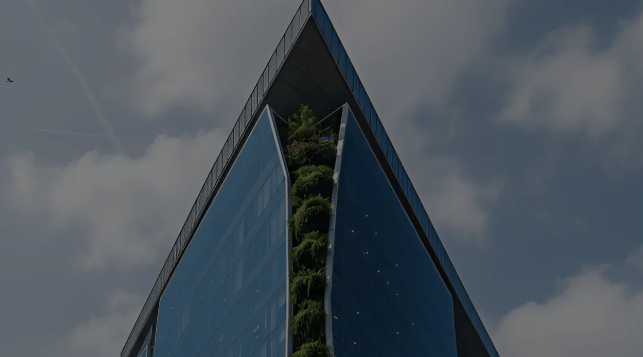 Sharp-angled modern building with reflective glass facade and vertical garden in the middle under a partly cloudy sky.