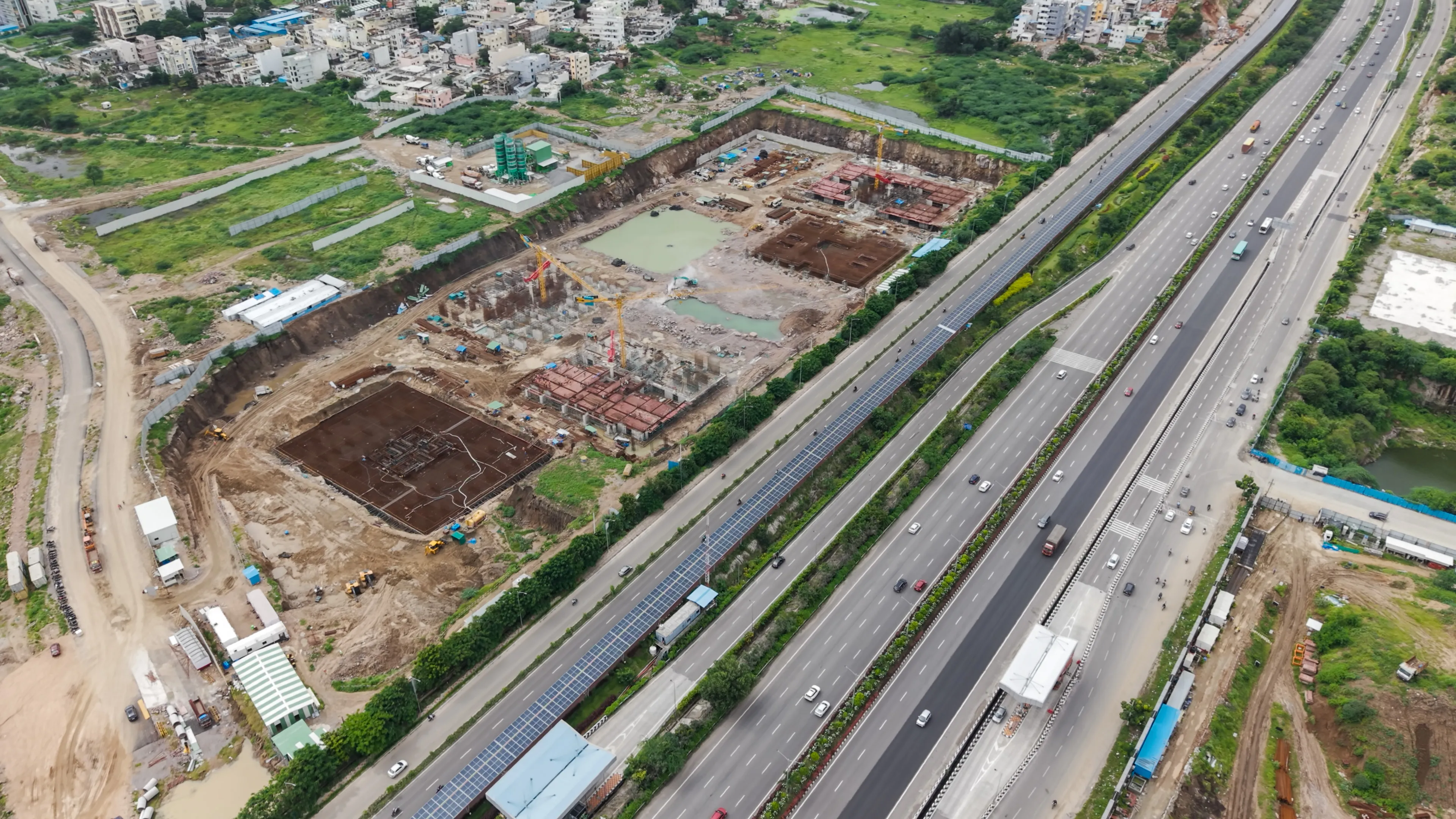 Aerial view of a construction site next to a multi-lane highway with solar panels installed along the median.