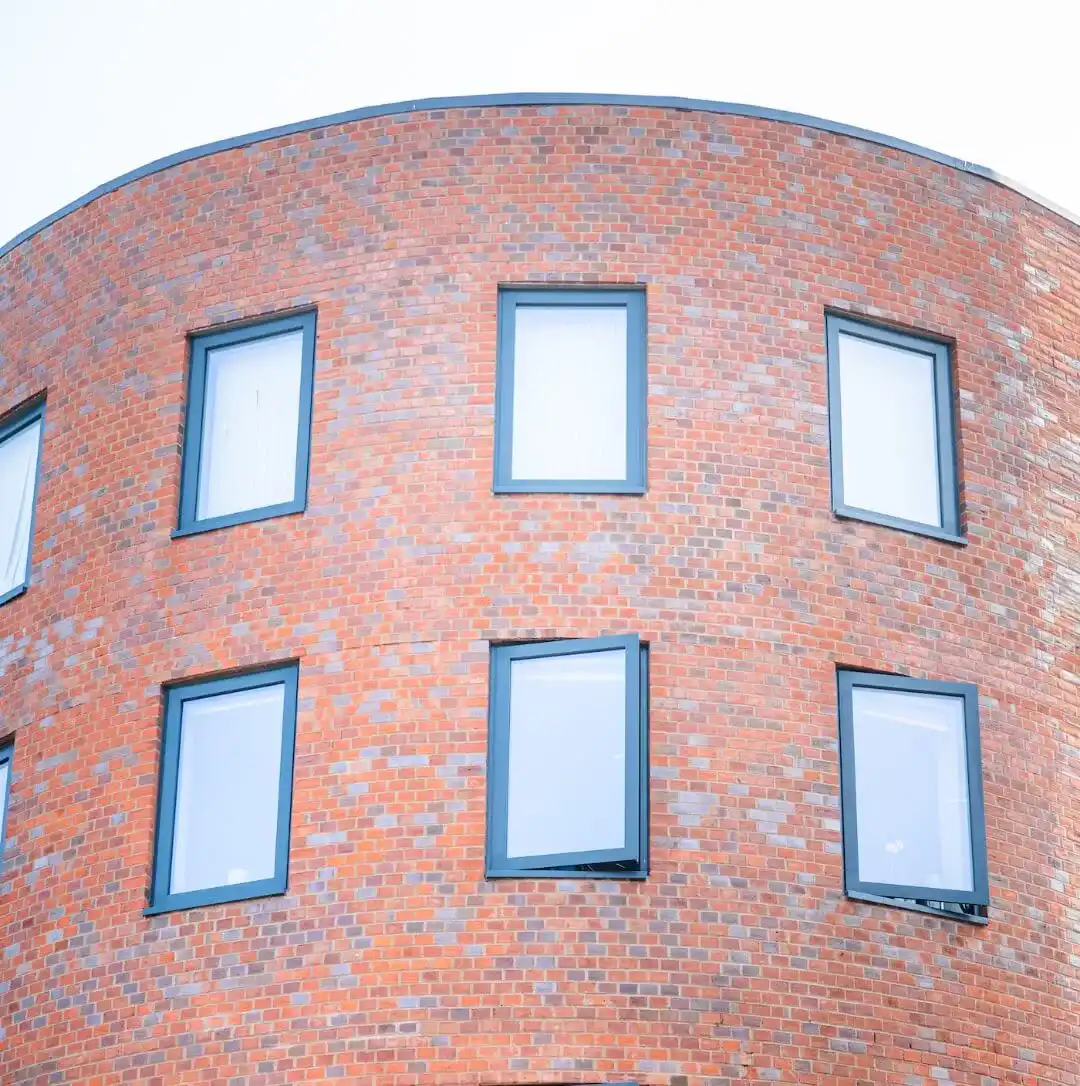 Curved red brick façade with framed windows and a smooth contemporary architectural form