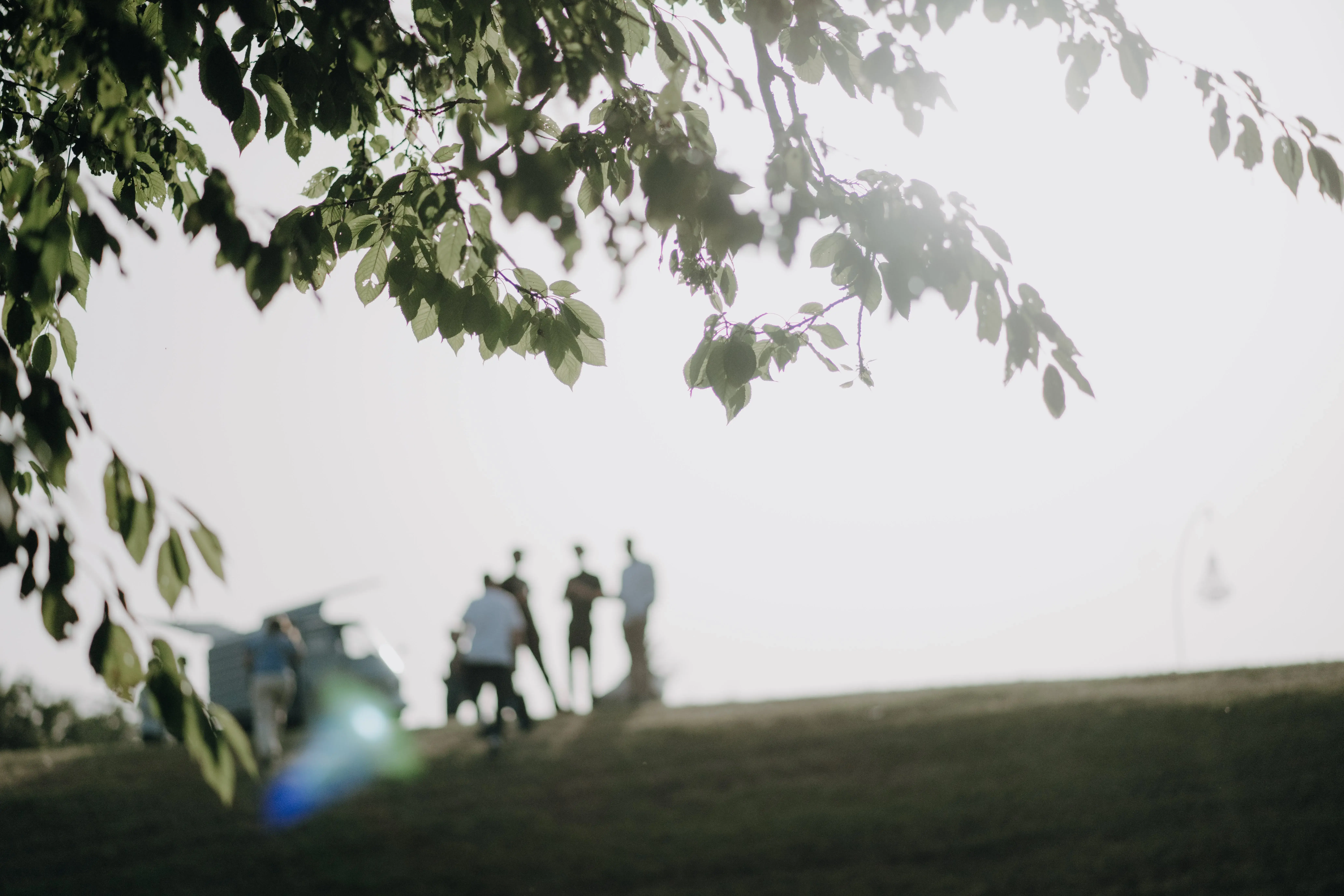 A group of people standing in the distance on a hill