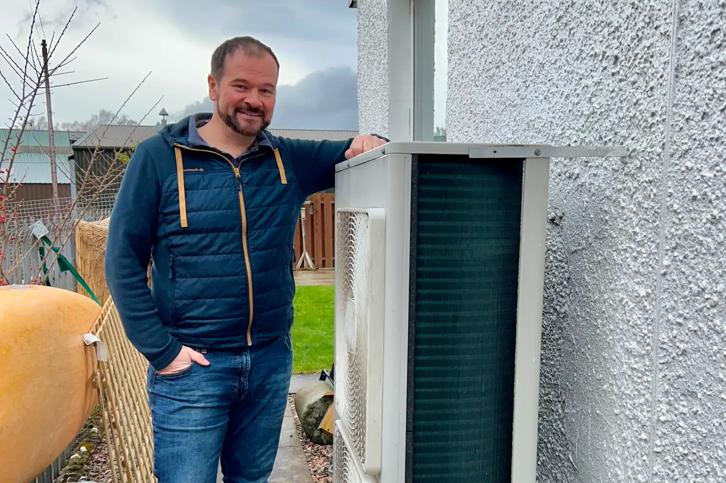 A man standing next to a heat pump.