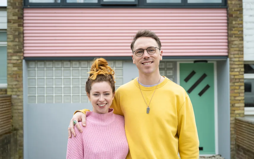 A man and a woman standing in front of a house.