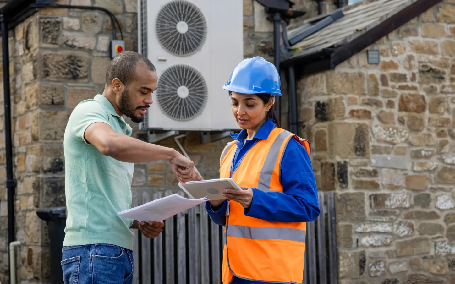 A man and a woman in hardhats are looking at a piece of paper.
