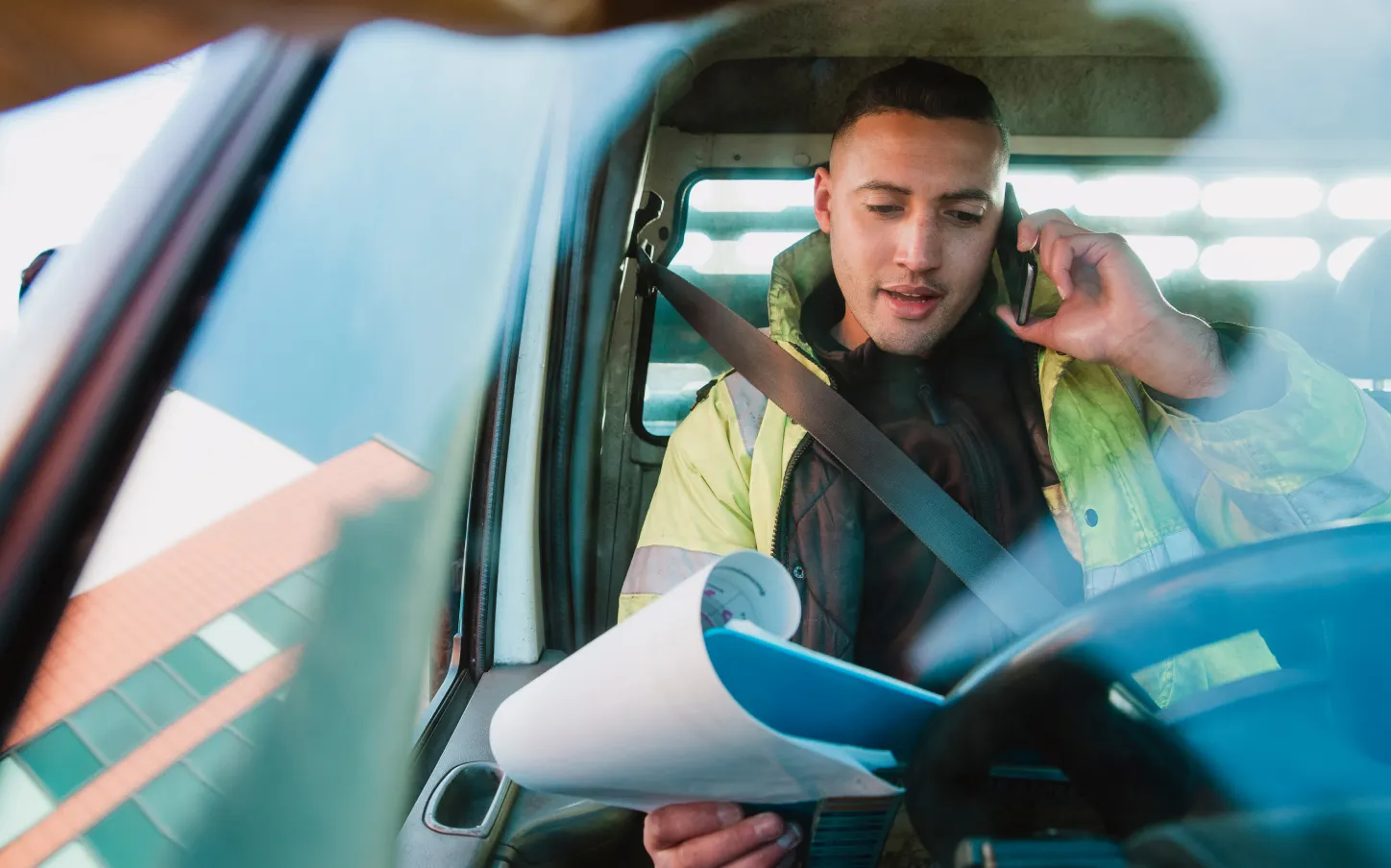 A man sitting in a car talking on a cell phone.