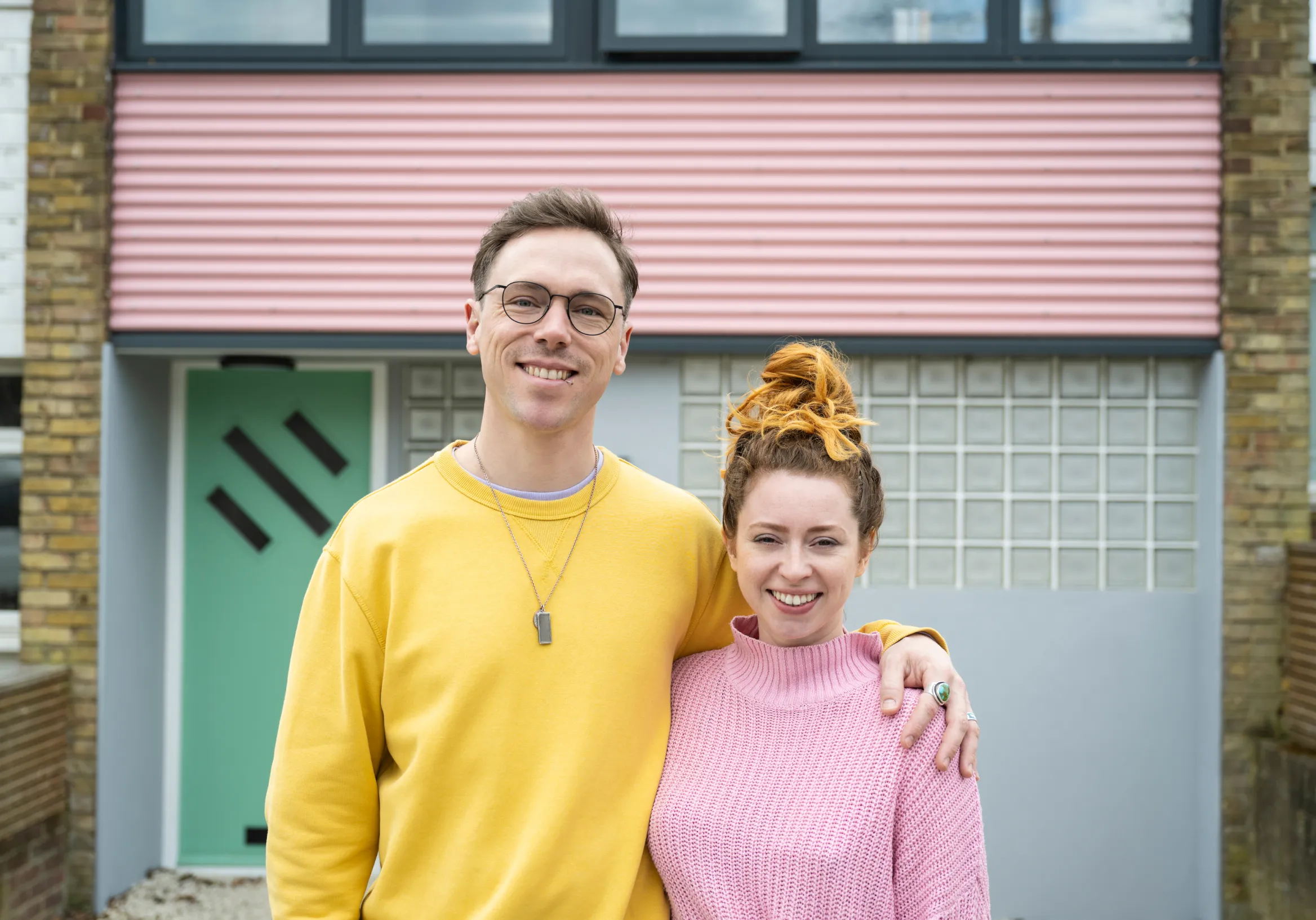 A man and woman smiling in front of the house