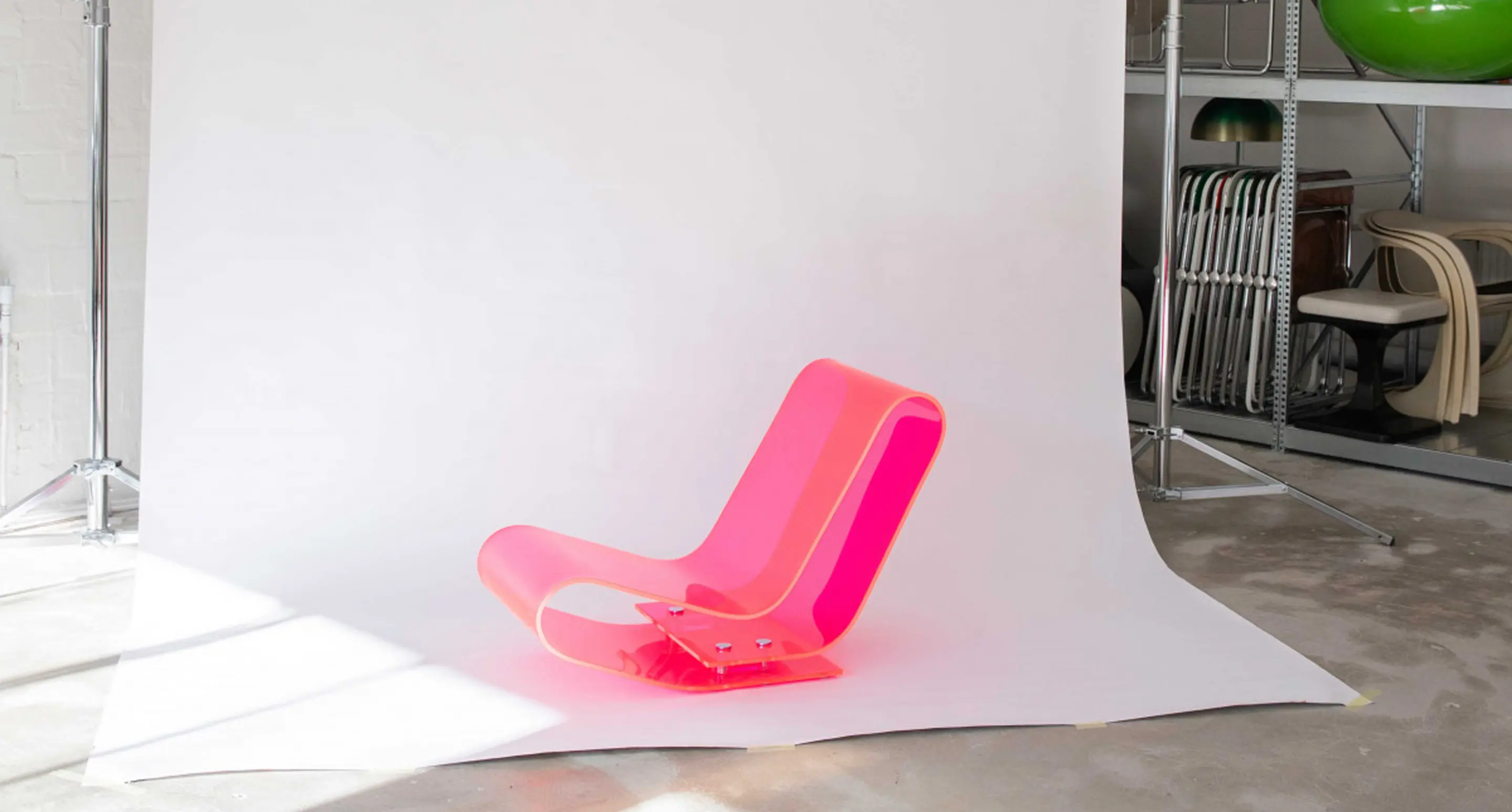 Futuristic pink acrylic chair in a photo studio setup with a white backdrop