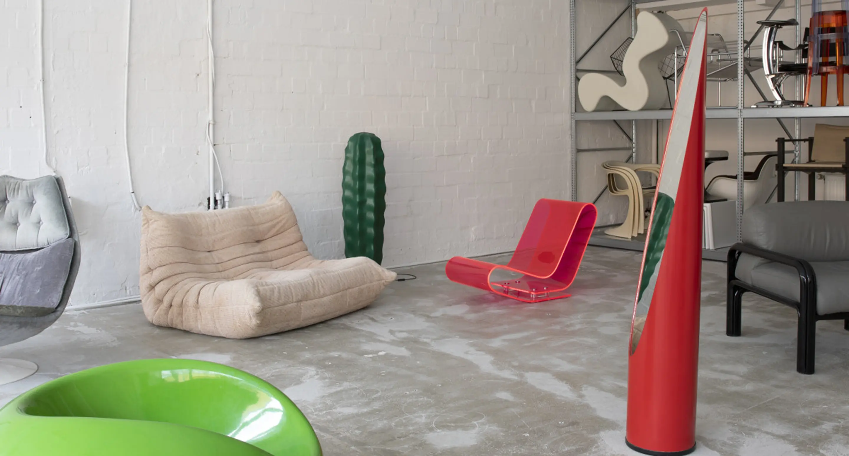 Eclectic room with beige modular sofa, neon pink acrylic chair, green pod chair, and decorative cactus sculpture