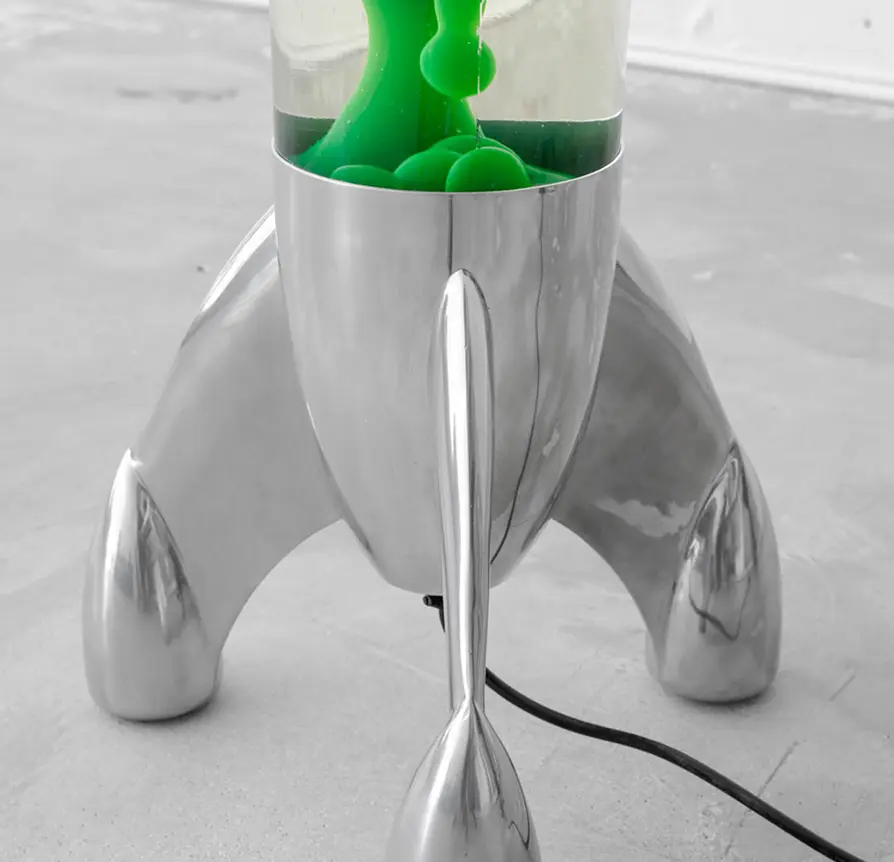 Retro rocket-shaped lava lamp with green wax on a concrete floor