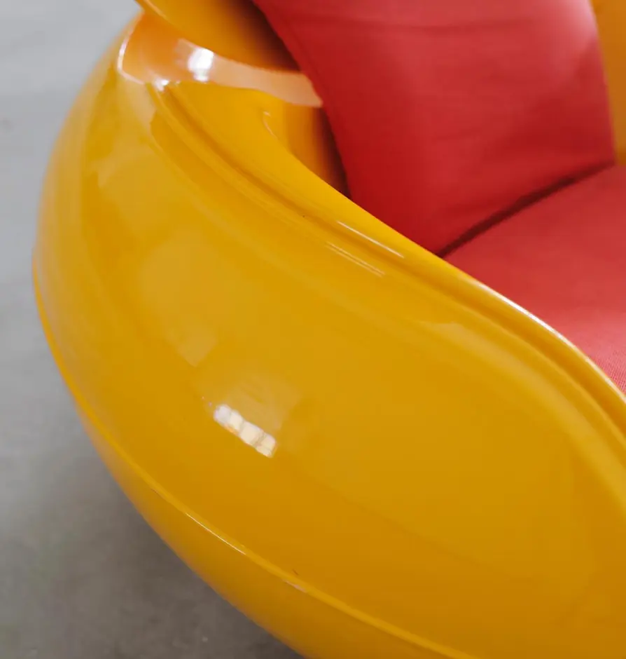 Close-up of glossy orange frame and red upholstery of modern lounge chair
