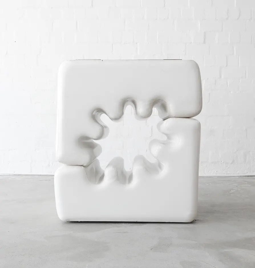 White sculptural lounge chair with gear-like indentation.