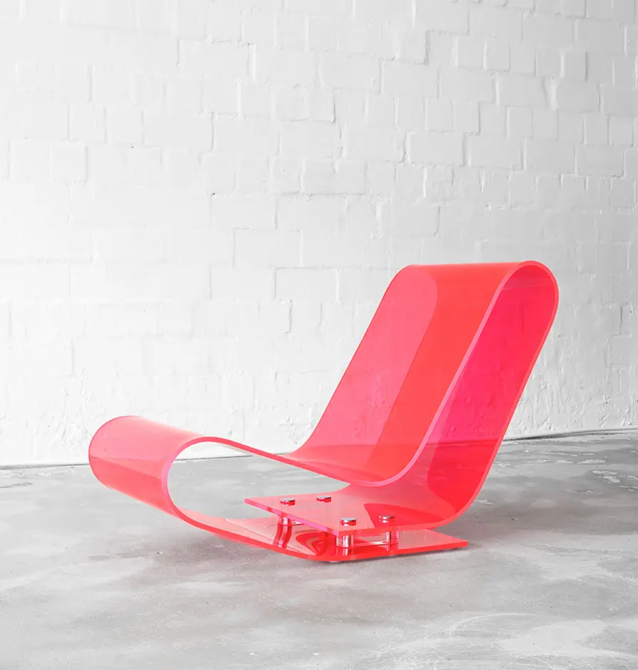 Modern sculptural lounge chair in translucent pink acrylic with a curved form