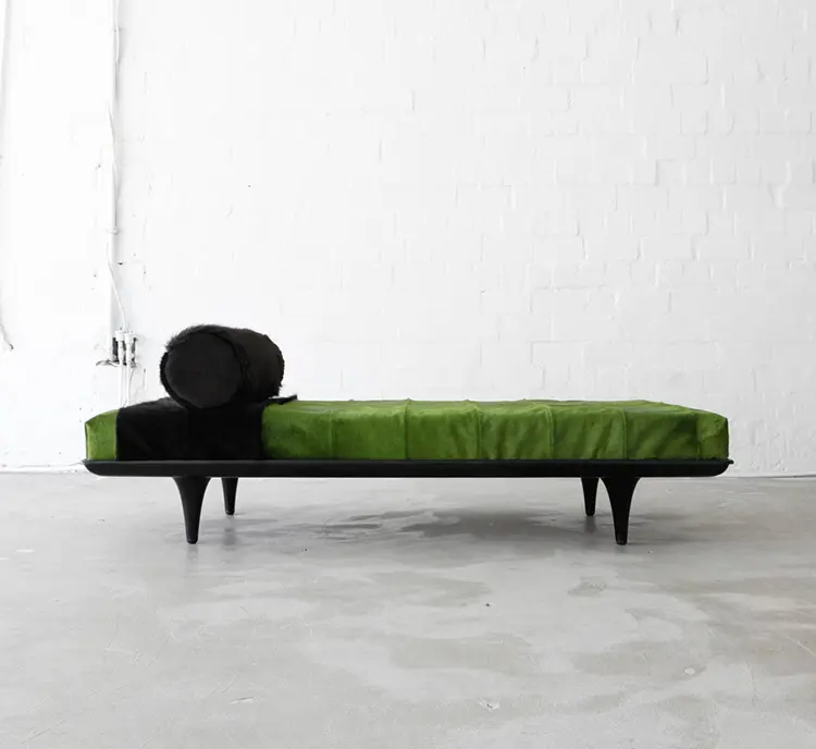 Modern daybed with green and black fur-like upholstery and black tapered legs