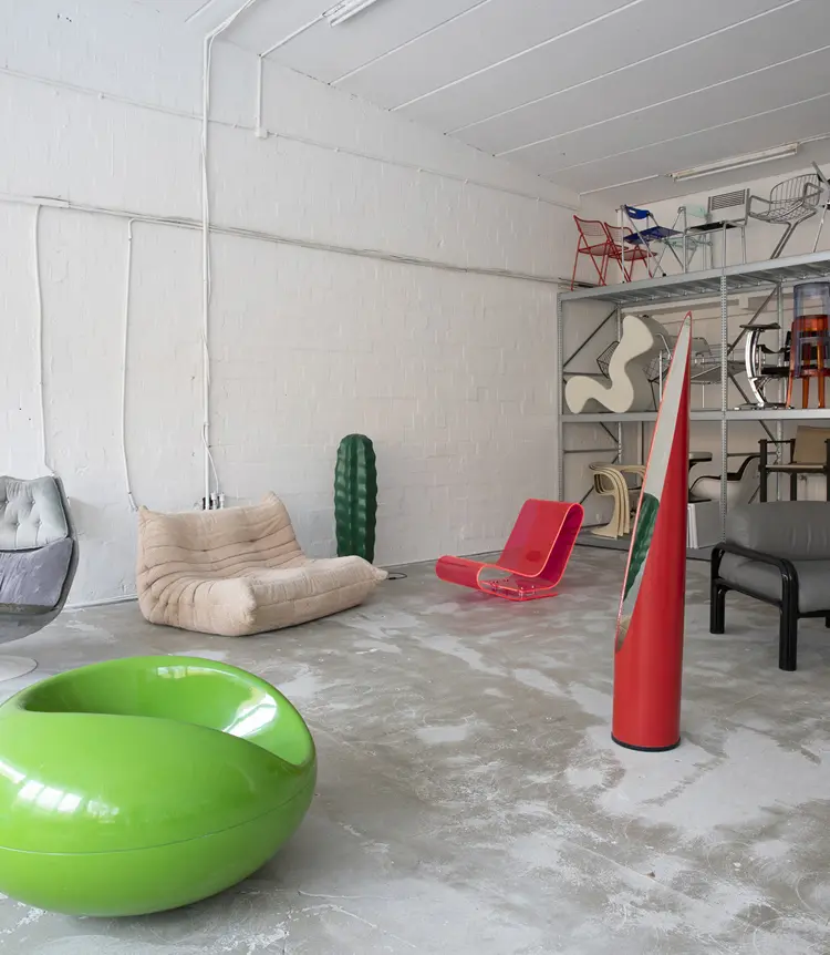 Eclectic room with beige modular sofa, neon pink acrylic chair, green pod chair, and decorative cactus sculpture