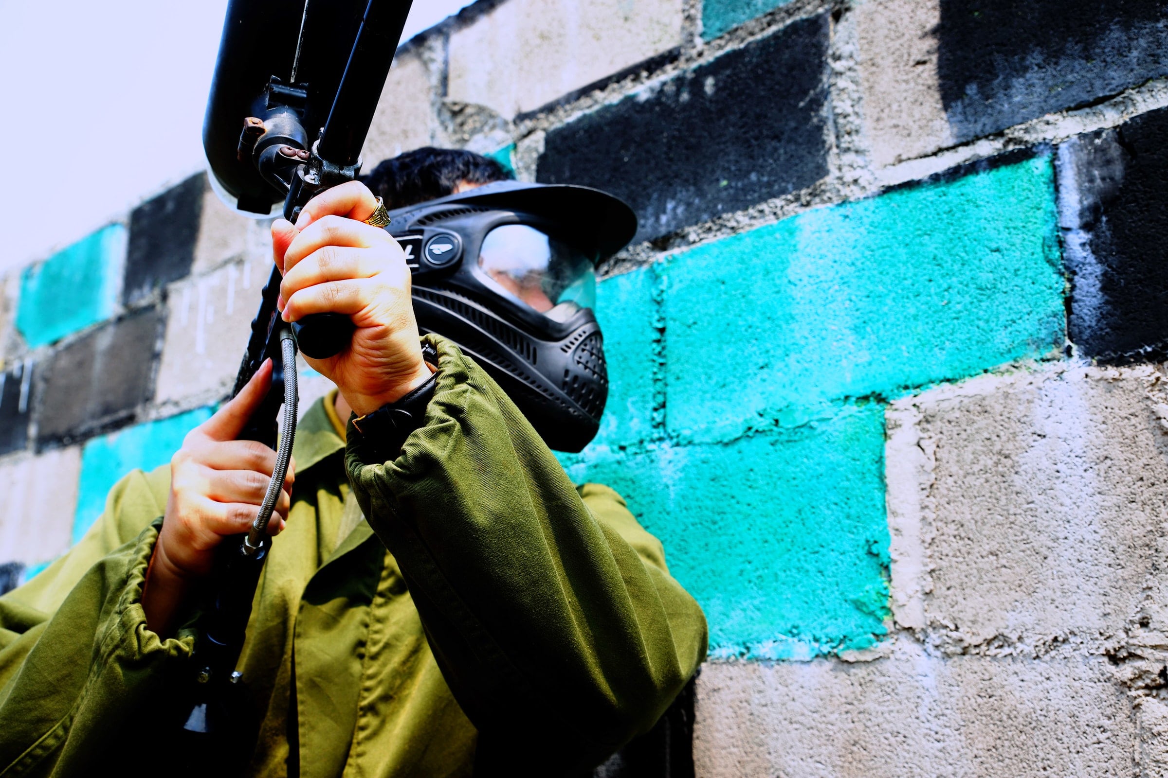 Person wearing paintball mask and holding paintball gun