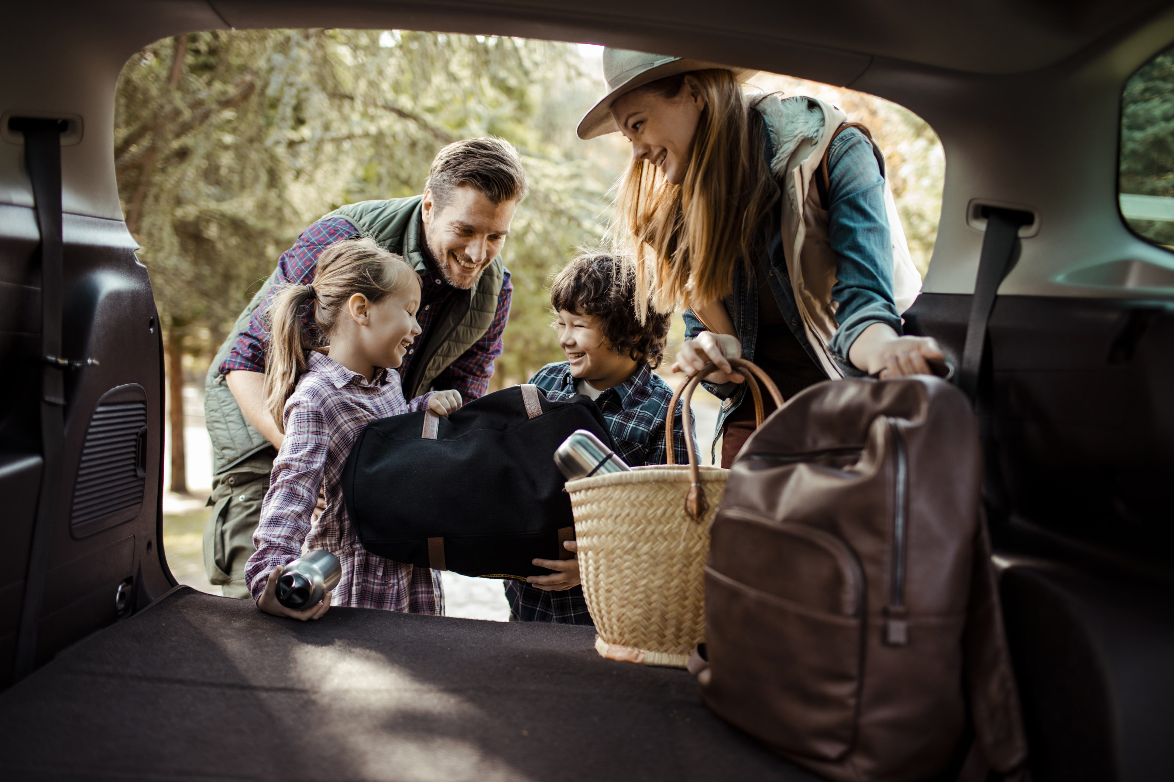 Young family putting bags in trunk of car