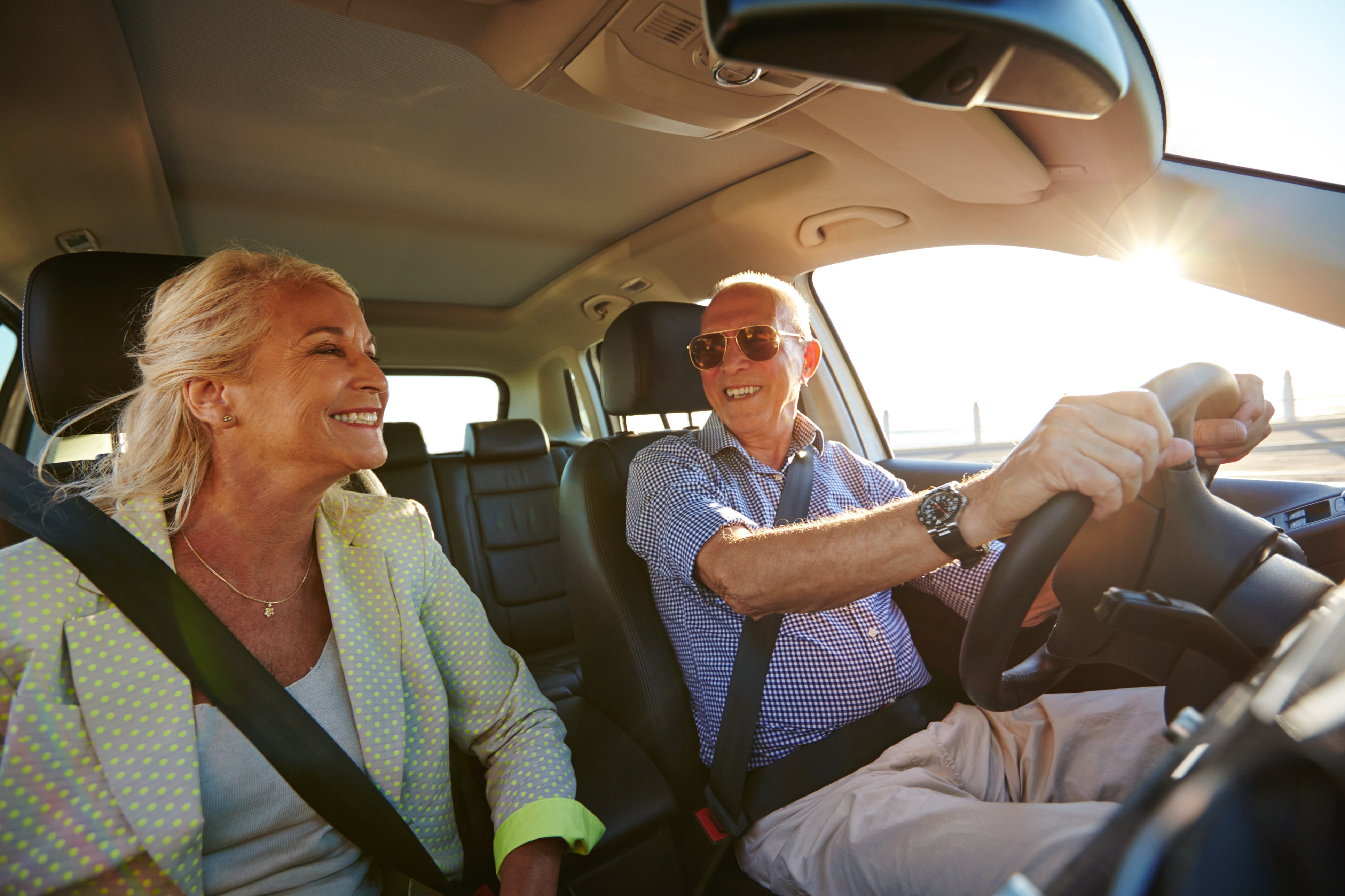 Senior couple driving in a car on a sunny day