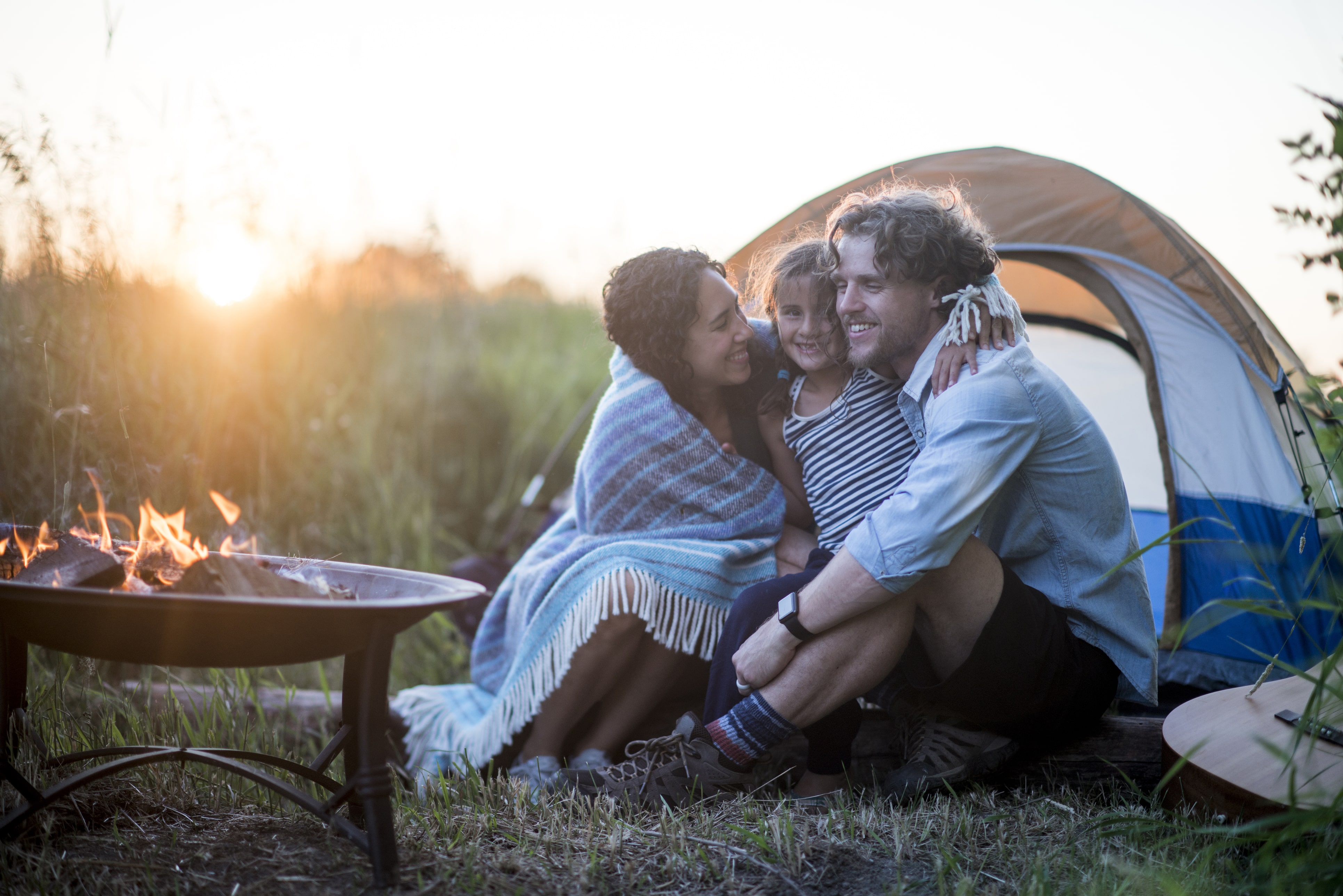 Young family sitting in front of a pitched tent