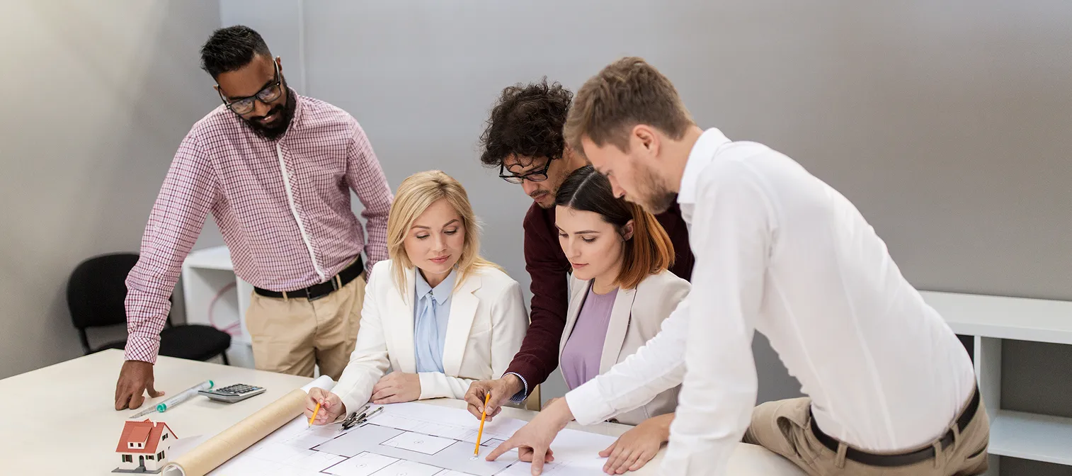 Real estate team reviewing property plans on a conference table.