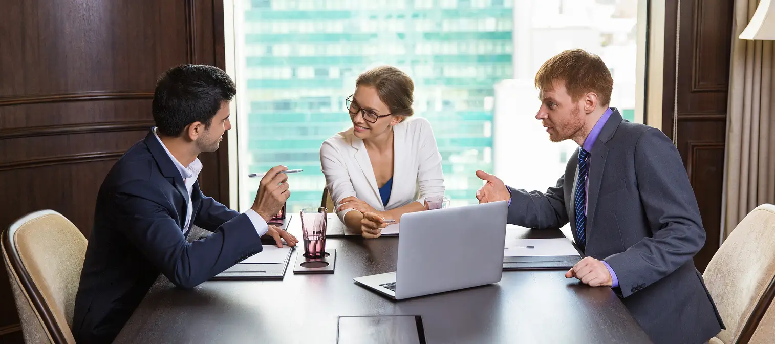 Group of professionals at a conference table, including a lawyer reviewing documents for signing