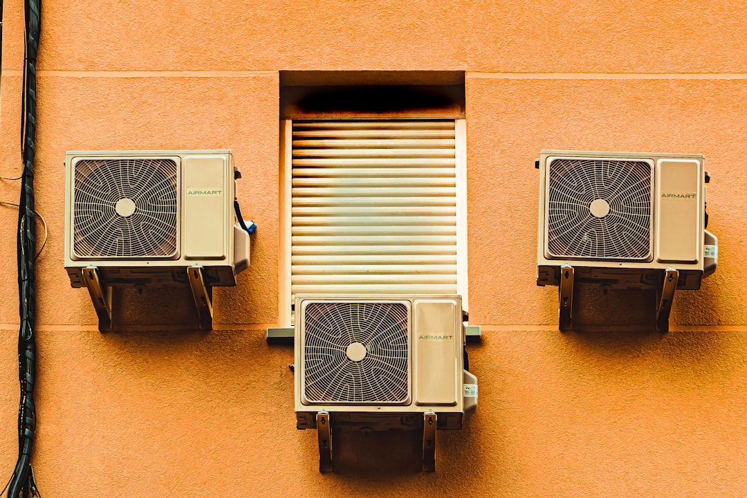 technician using a garden hose to gently clean condenser coils on an outdoor AC unit