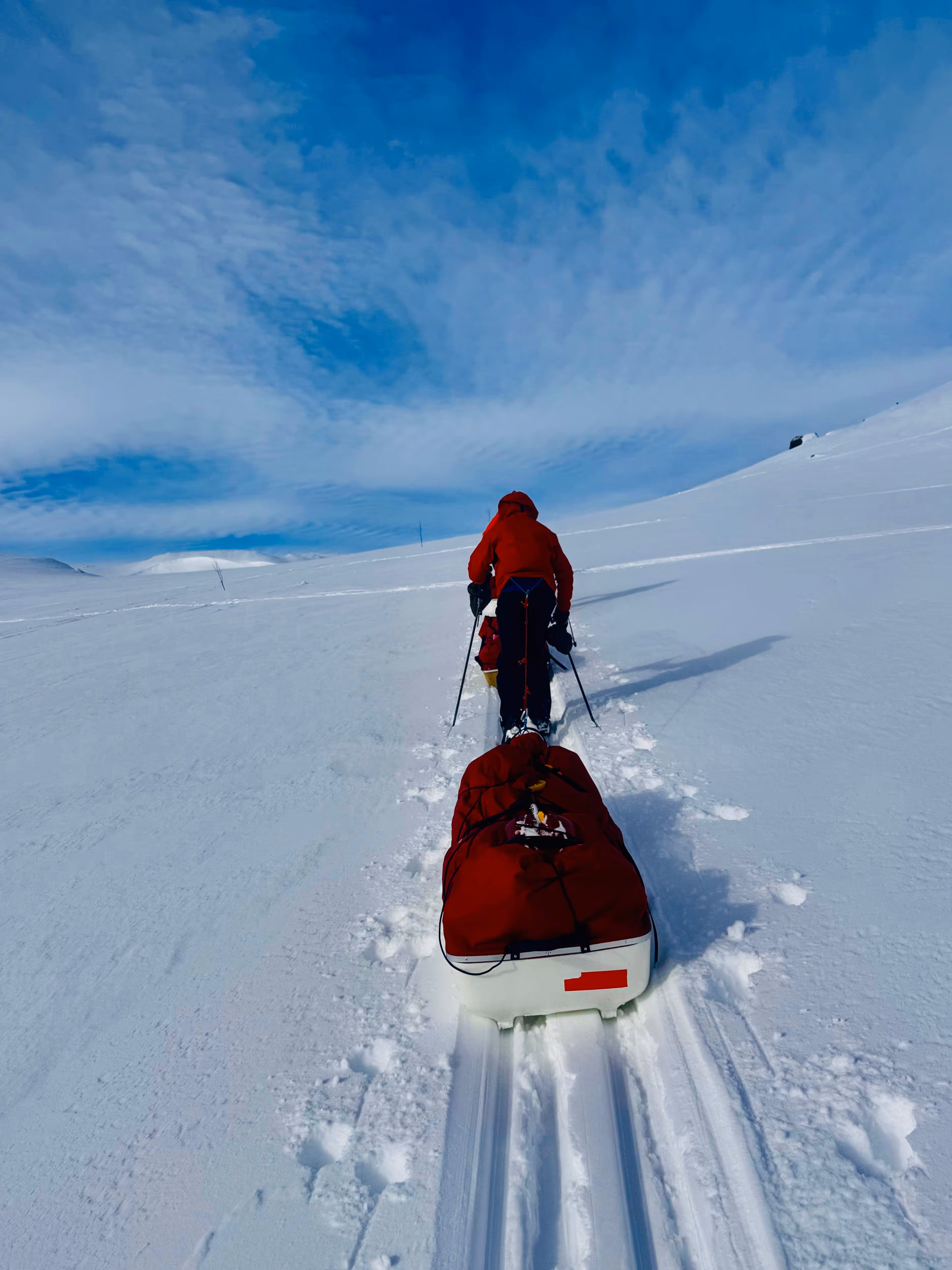 A person is skiing down a snowy mountain with a red backpack.