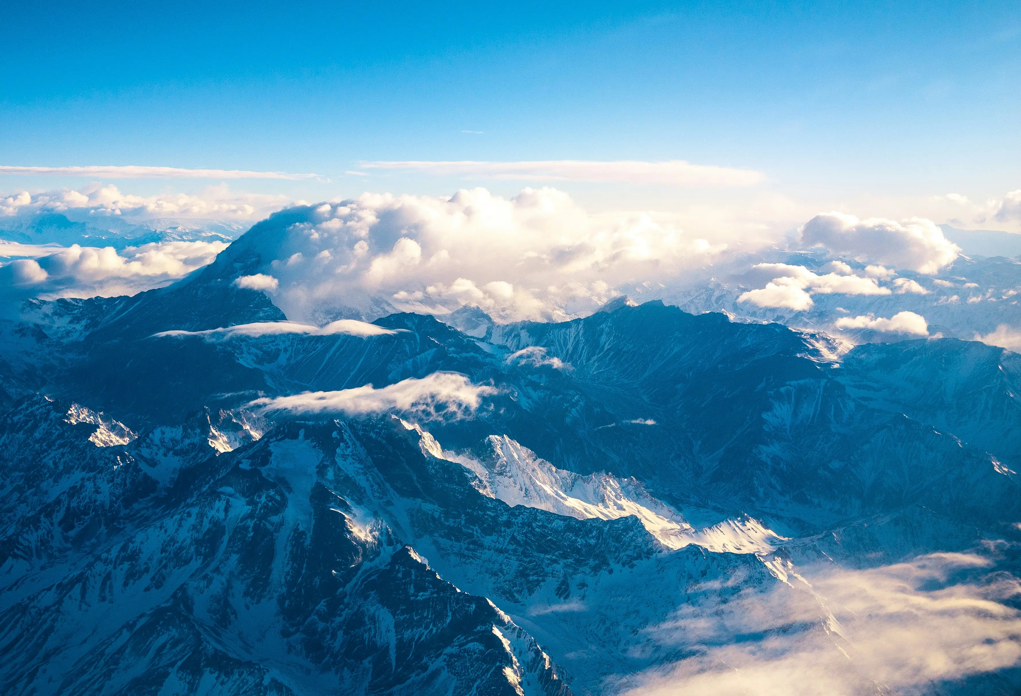 Aerial view of the snow covered Andes around Aconcagua, with cloud lying between the ridges
