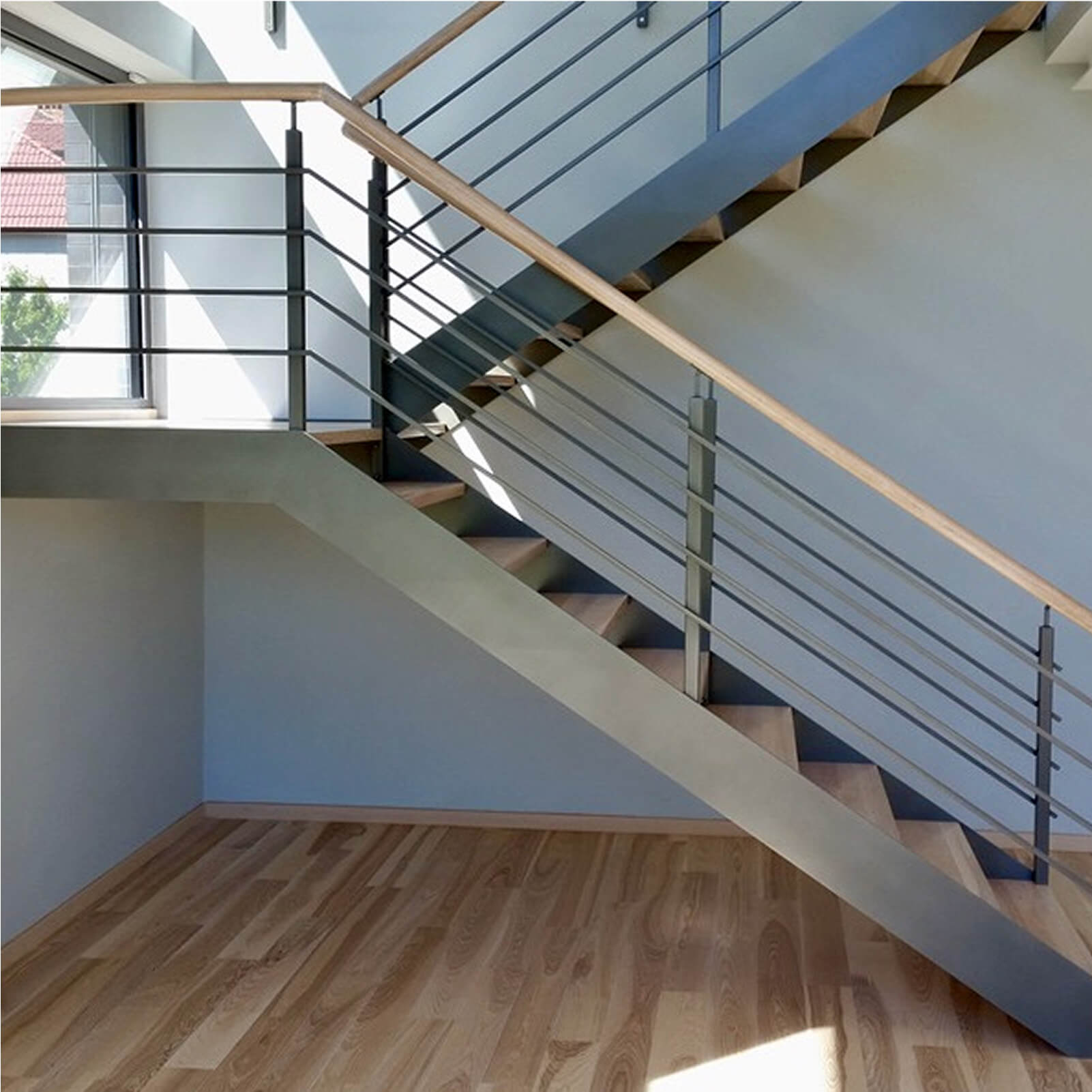 Nowoczesne schody L-kształtne z malowanym stalowym stringerem, dębowymi stopniami i balustradą z poziomych prętów