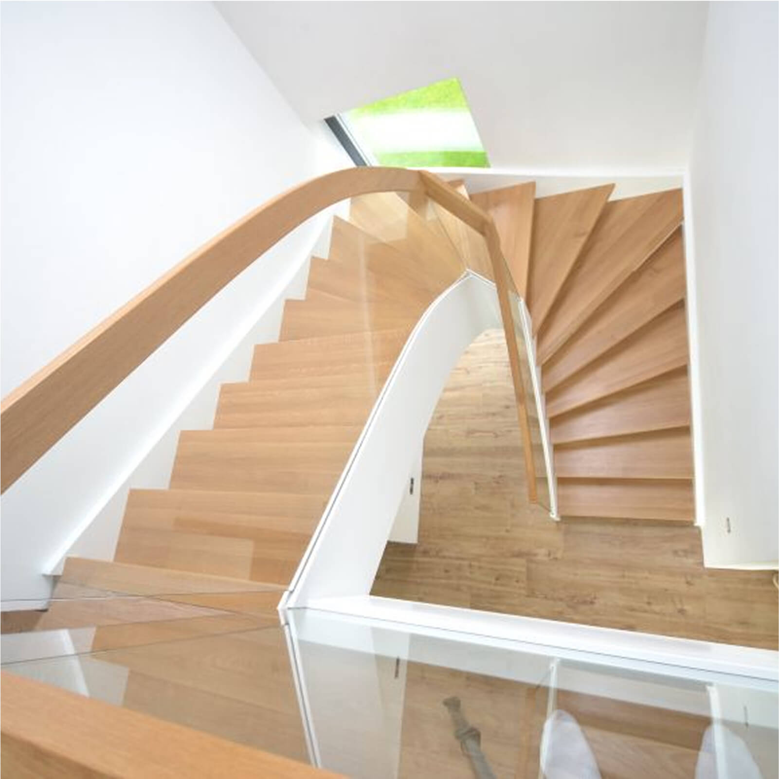 Nowoczesne schody zabiegowe z dębowymi stopniami i przeszkloną balustradą