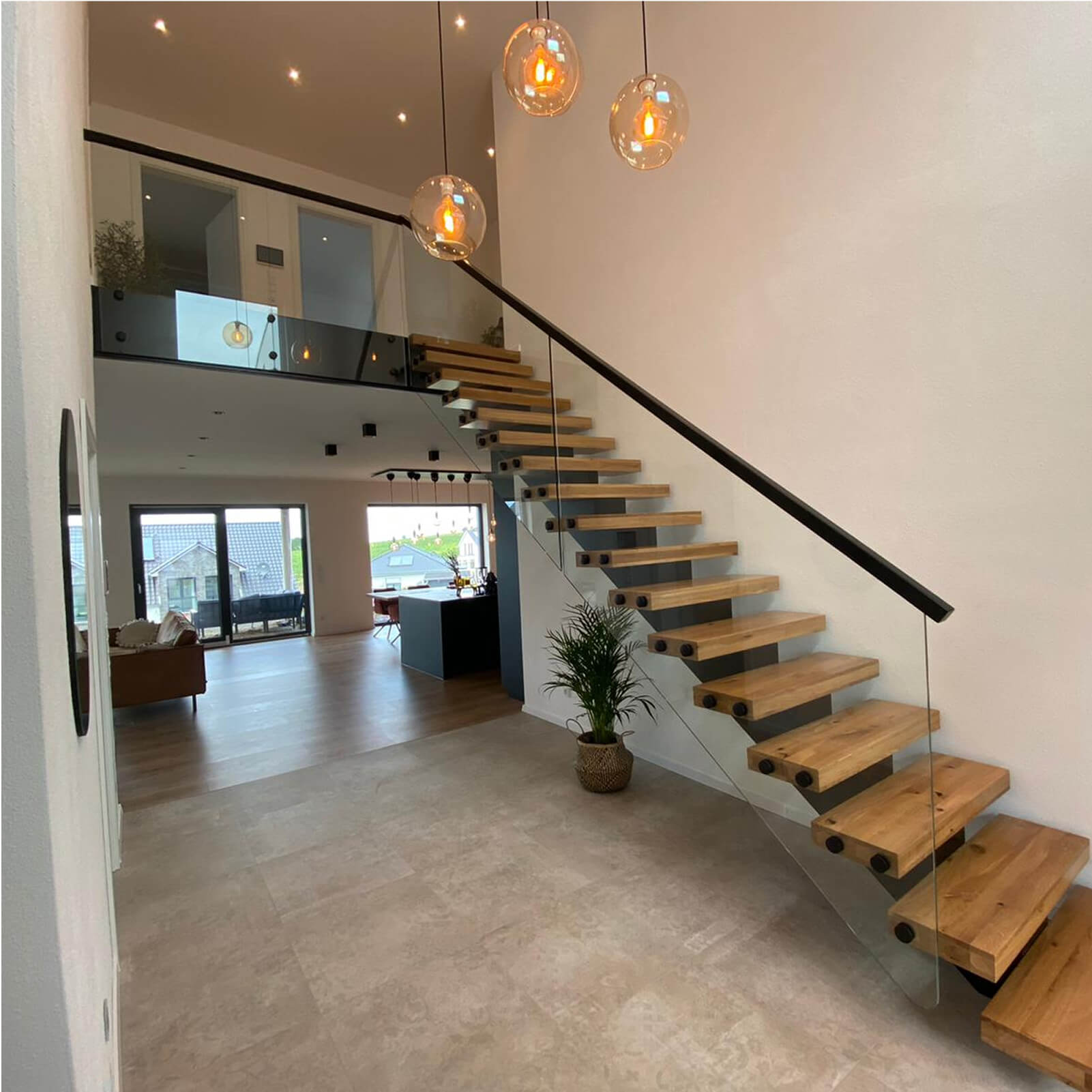 Floating stairs z naturalnego drewna i hartowanego szkła w przestronnym wnętrzu