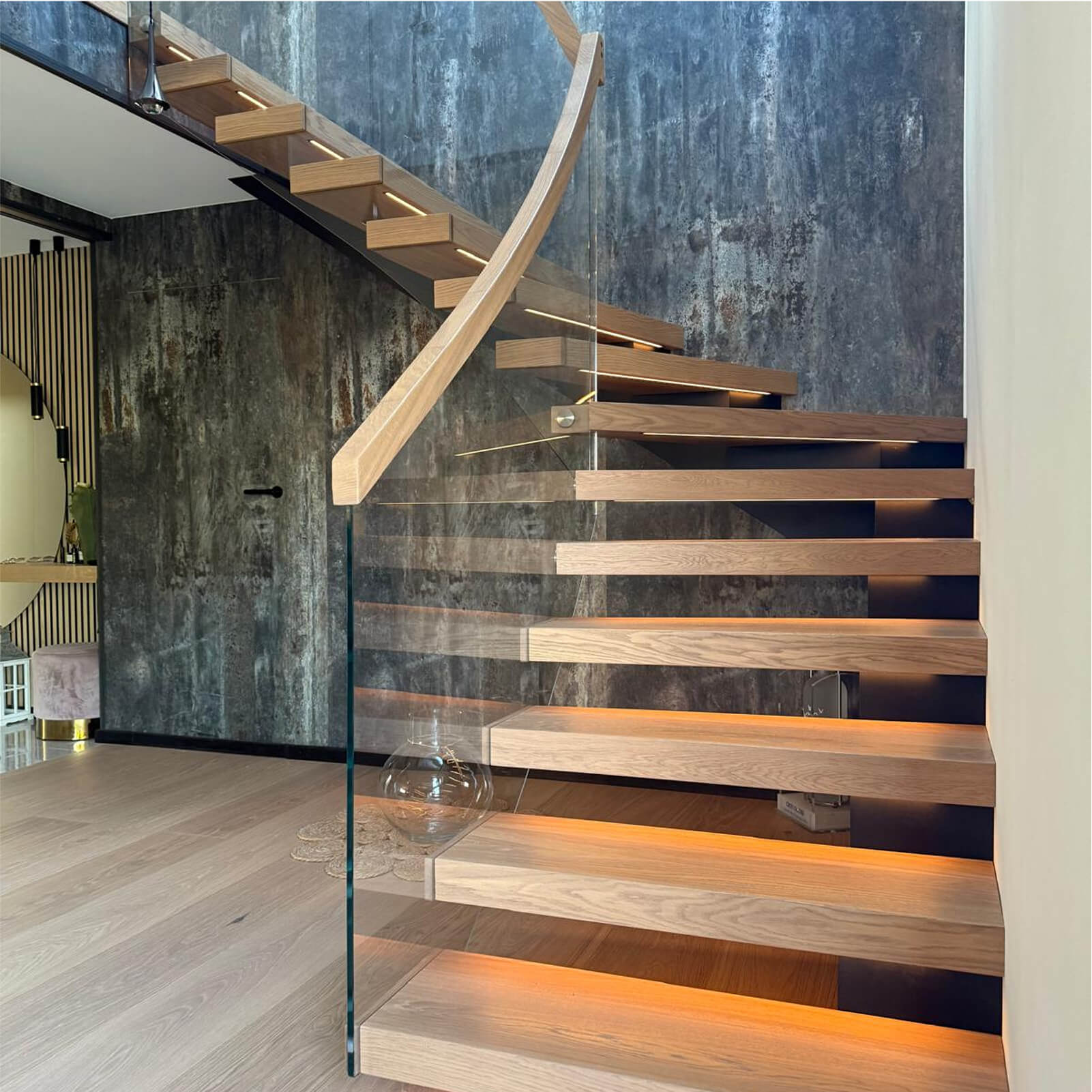 Designerskie schody wiszące z masywnymi dębowymi stopniami i transparentną barierką szklaną, subtelne oświetlenie LED