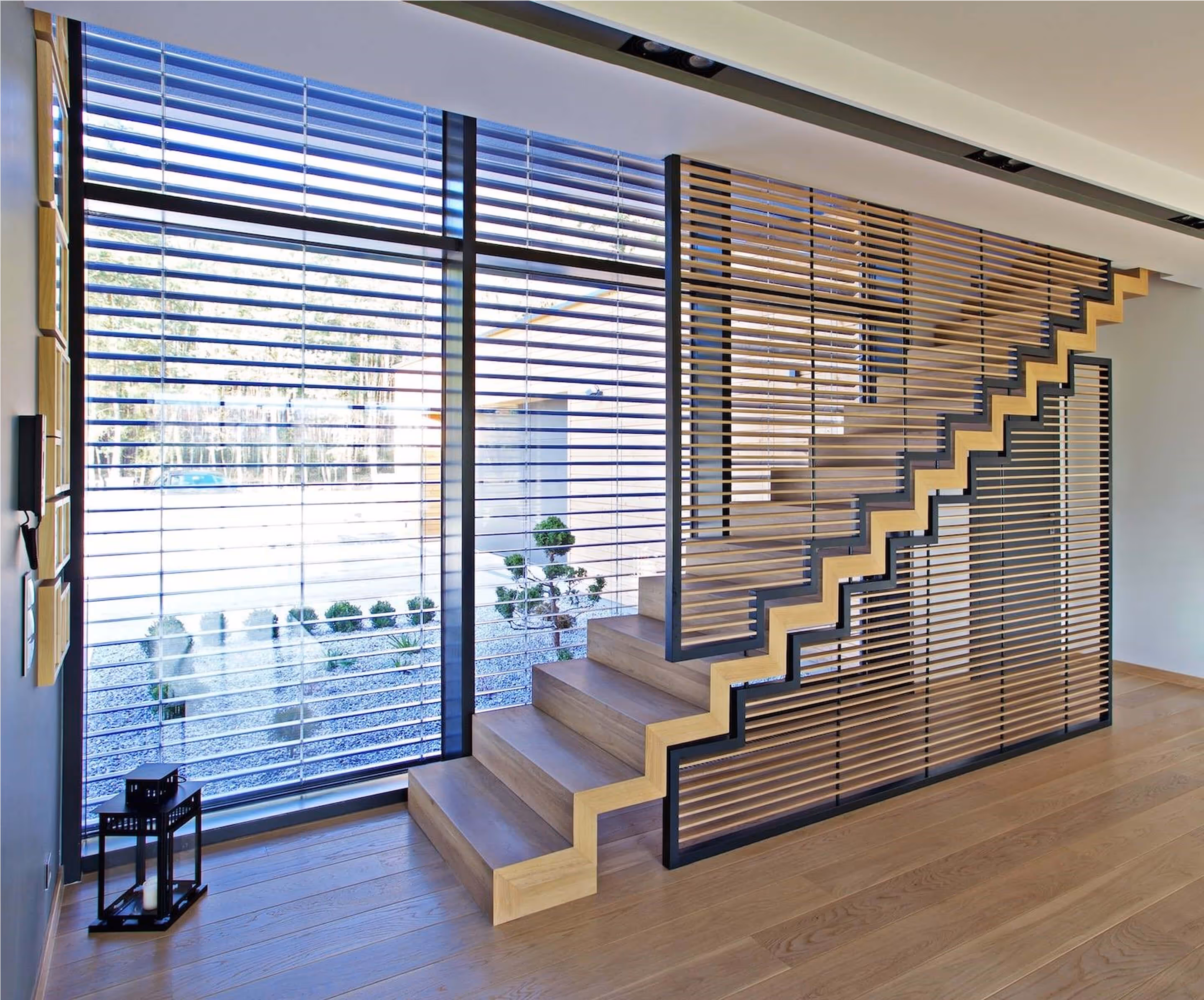 Minimalistyczne schody loftowe z drewnianymi stopniami, stalowym stelażem i dekoracyjnym panelem lamelowym