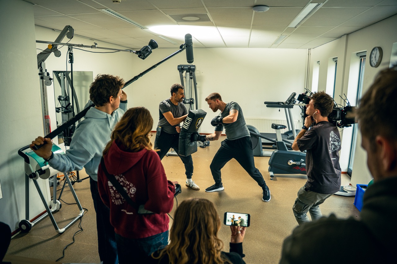 Filmcrew filmt een boksscène voor de brandfilm van Fivoor in een trainingsruimte.