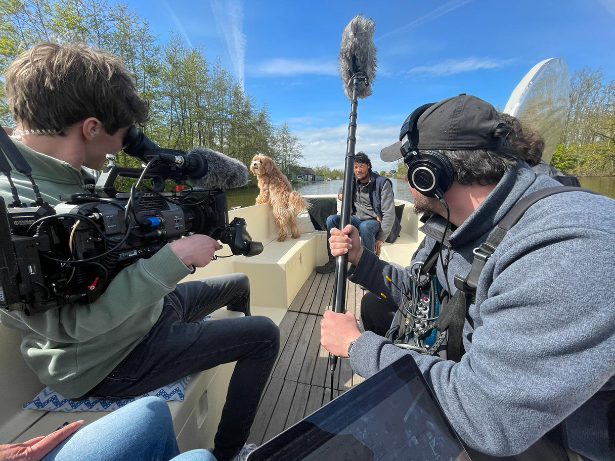 Filmcrew filmt hond Zwabber en een acteur tijdens een scène op een boot.