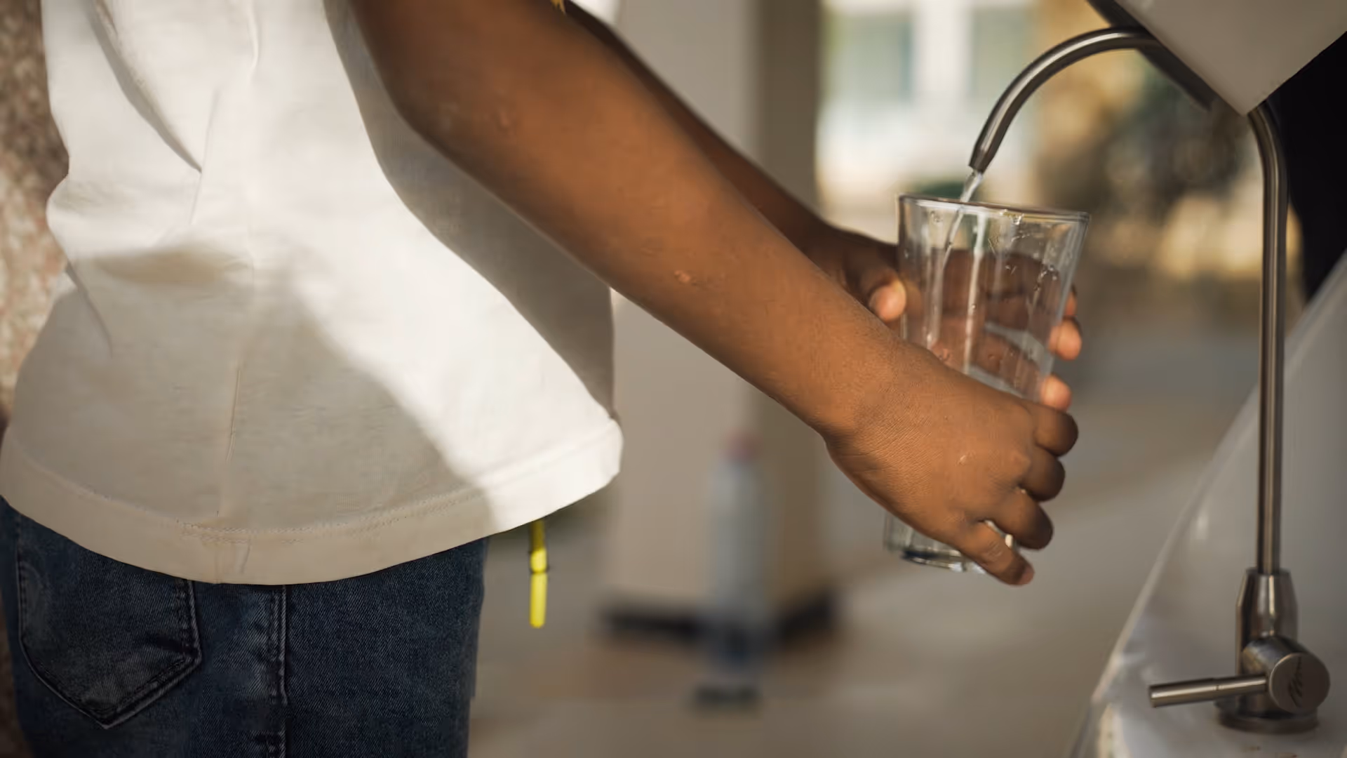 A child's hand is visible dispensing water from Kumulus' Amphore air-to-water generator.