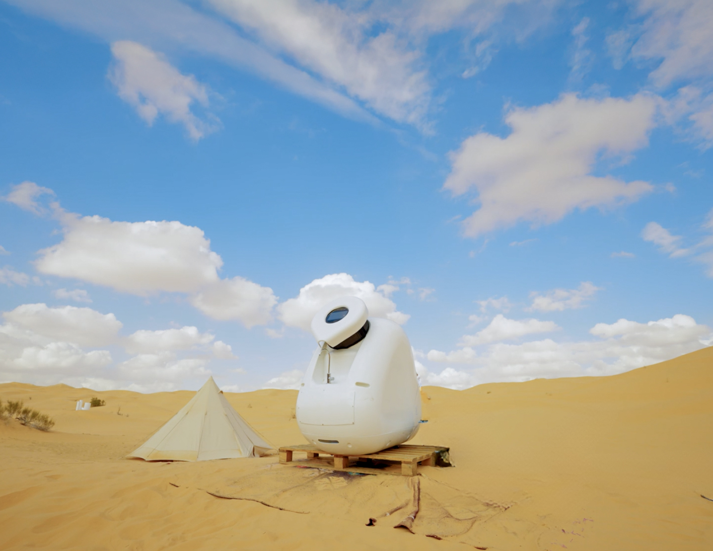 The Kumulus Amphore water-from-air solution placed on a wooden pallet, in the middle of a desert against a bright blue sky.