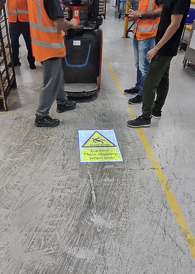 workers in facility with LED gobo projected warning on the floor