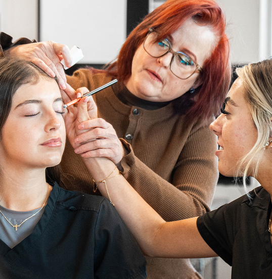 Instructor guiding an aesthetics student through hands-on skincare practice