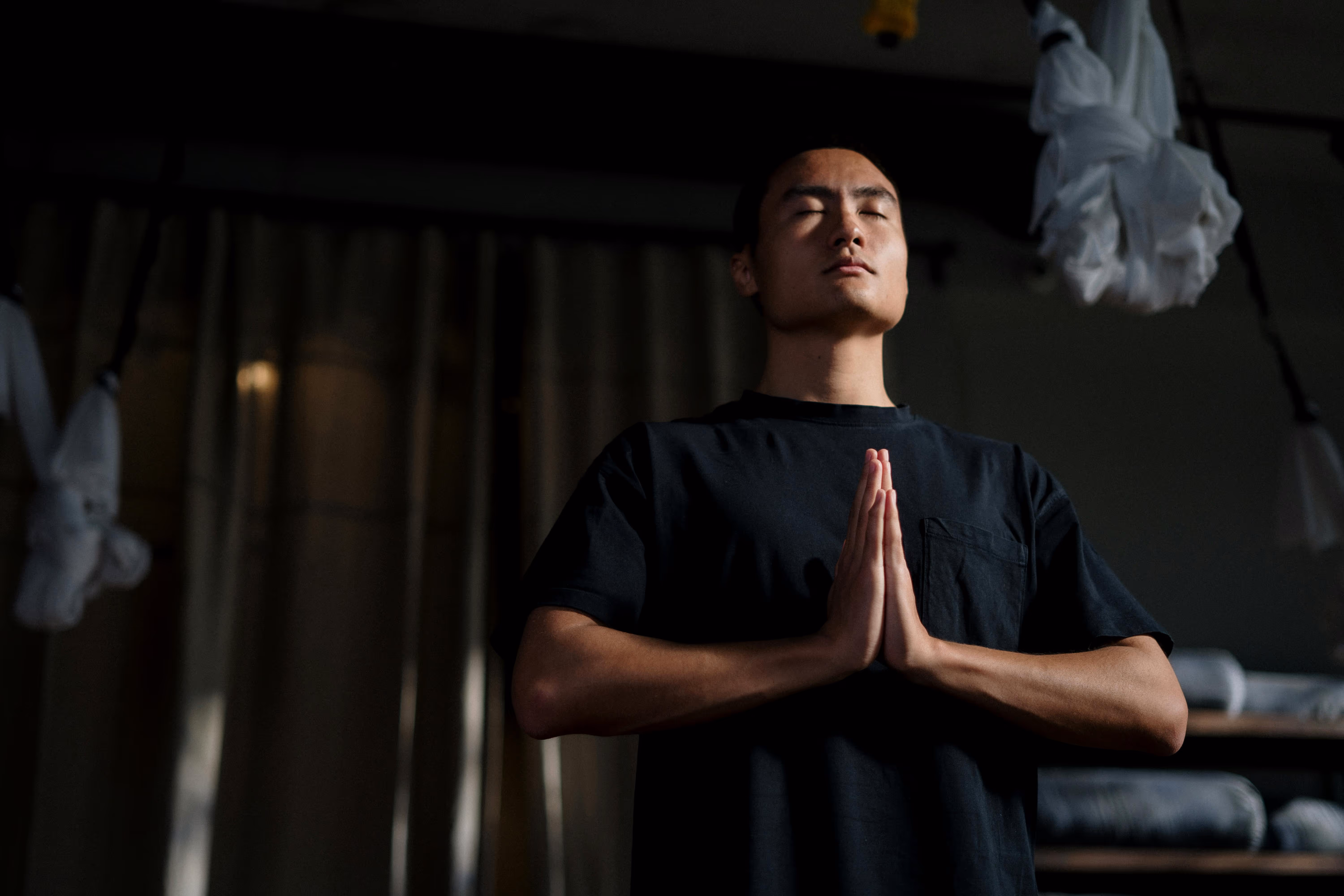 Man standing with hands in prayer position and eyes closed