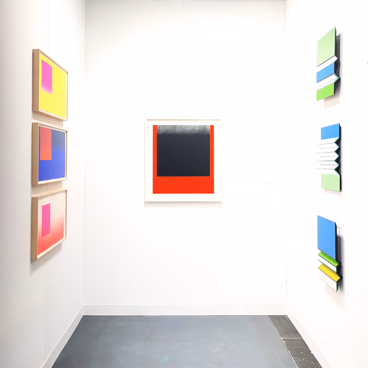 Galerie mit abstrakten Kunstwerken an hellen weißen Wänden, darunter ein rot-schwarzes quadratisches Gemälde im Zentrum.