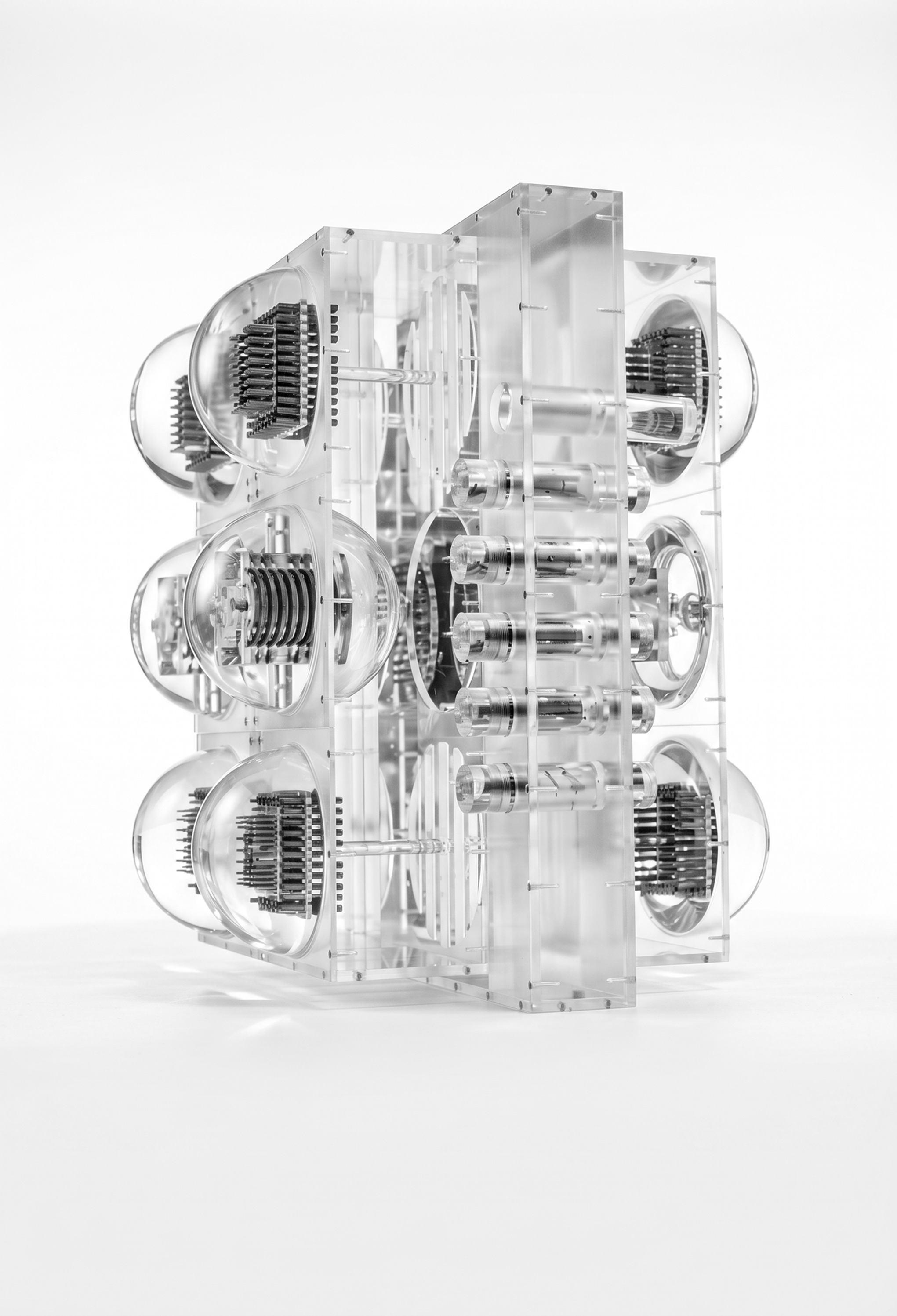 Transparente Acrylskulptur mit runden und zylindrischen eingebetteten Elementen auf weißem Hintergrund.