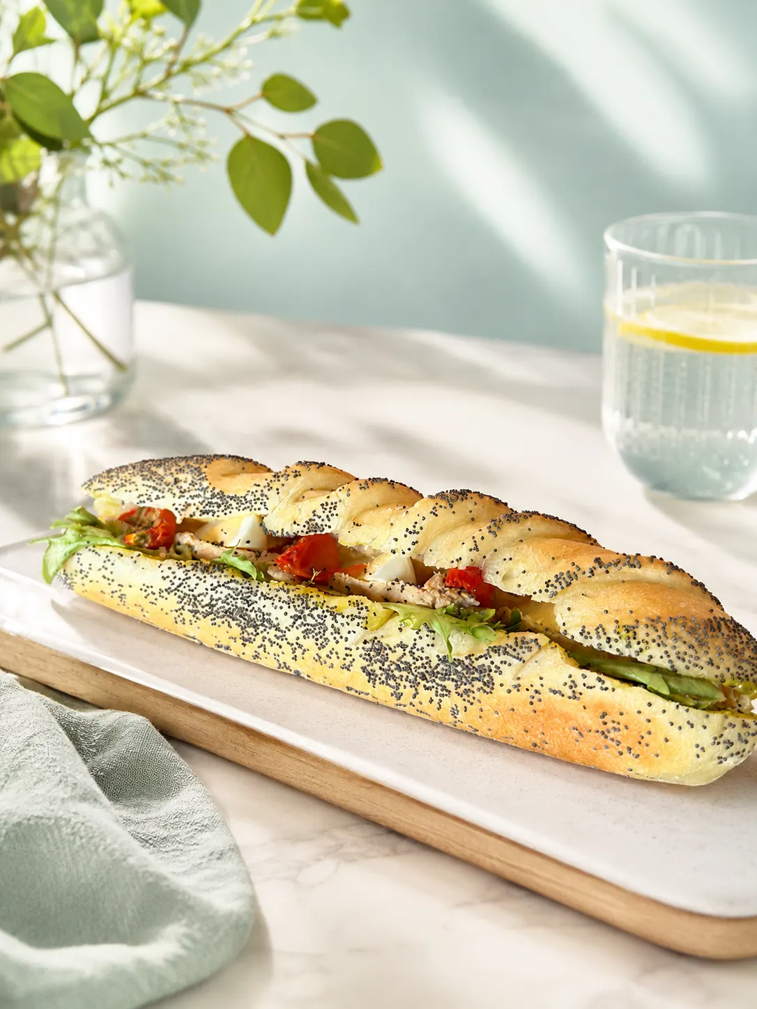 Sandwich viennois avec salade, tomates cerise et œufs sur une planche en bois.