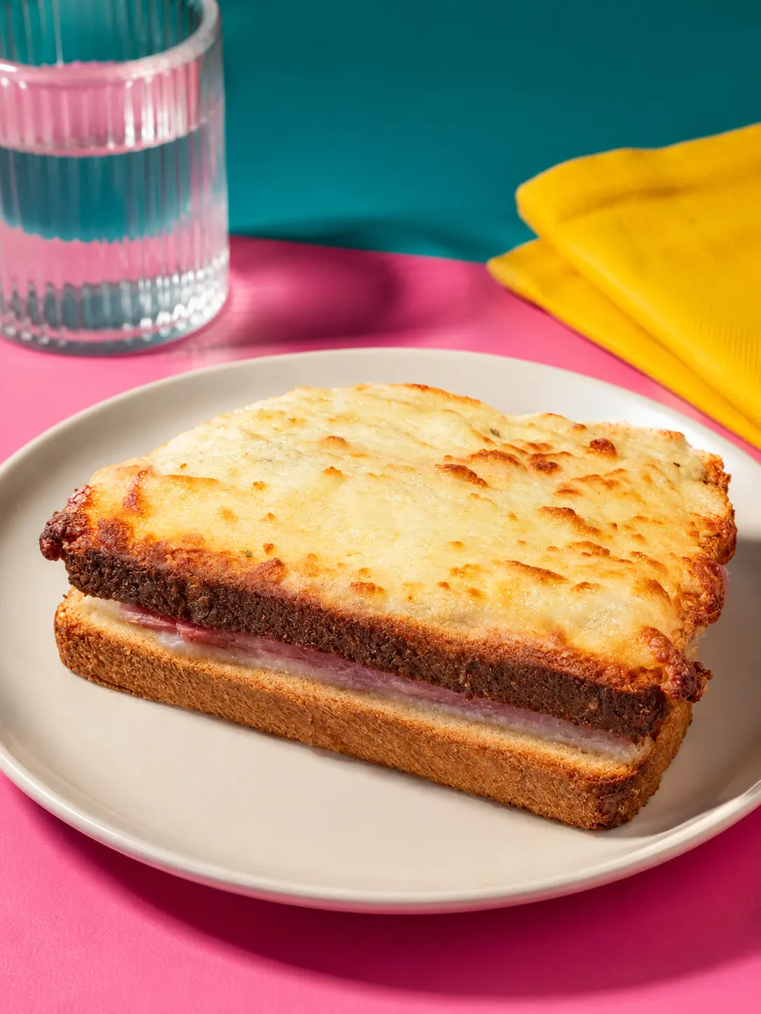 Croque-monsieur croustillant au fromage fondu et jambon sur assiette beige.