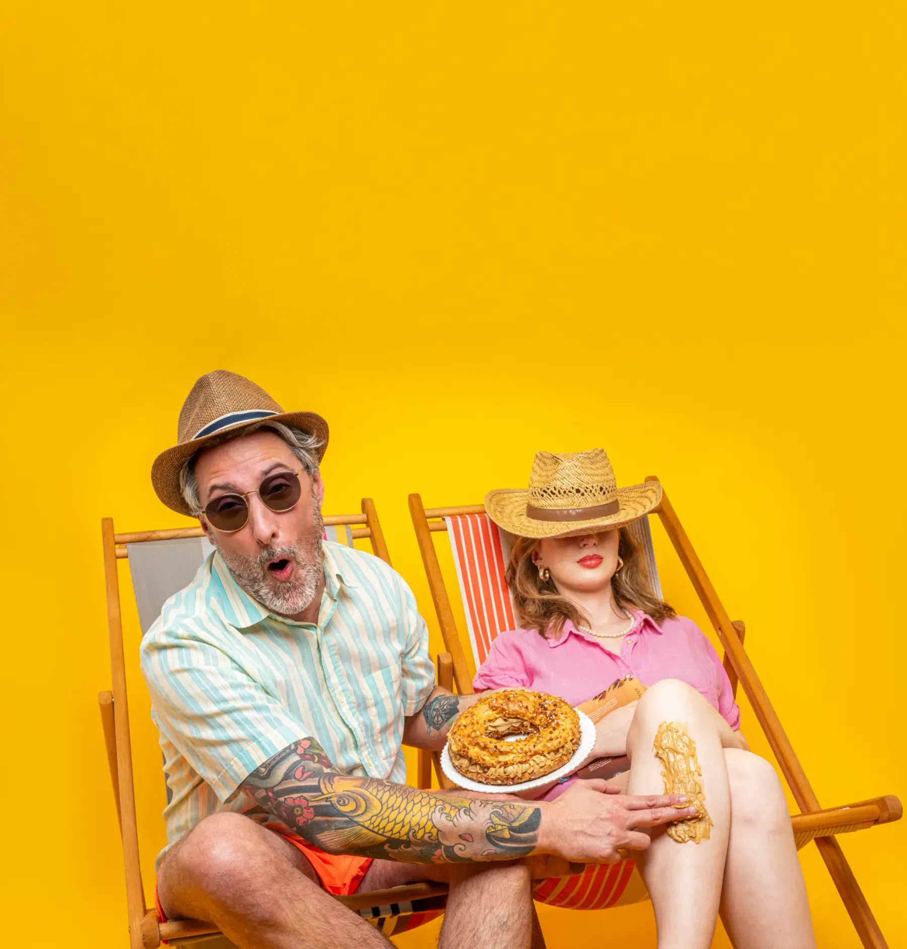 Un homme avec un tatouage applique du beurre de cacahuète sur la jambe d'une femme assise sur une chaise longue.