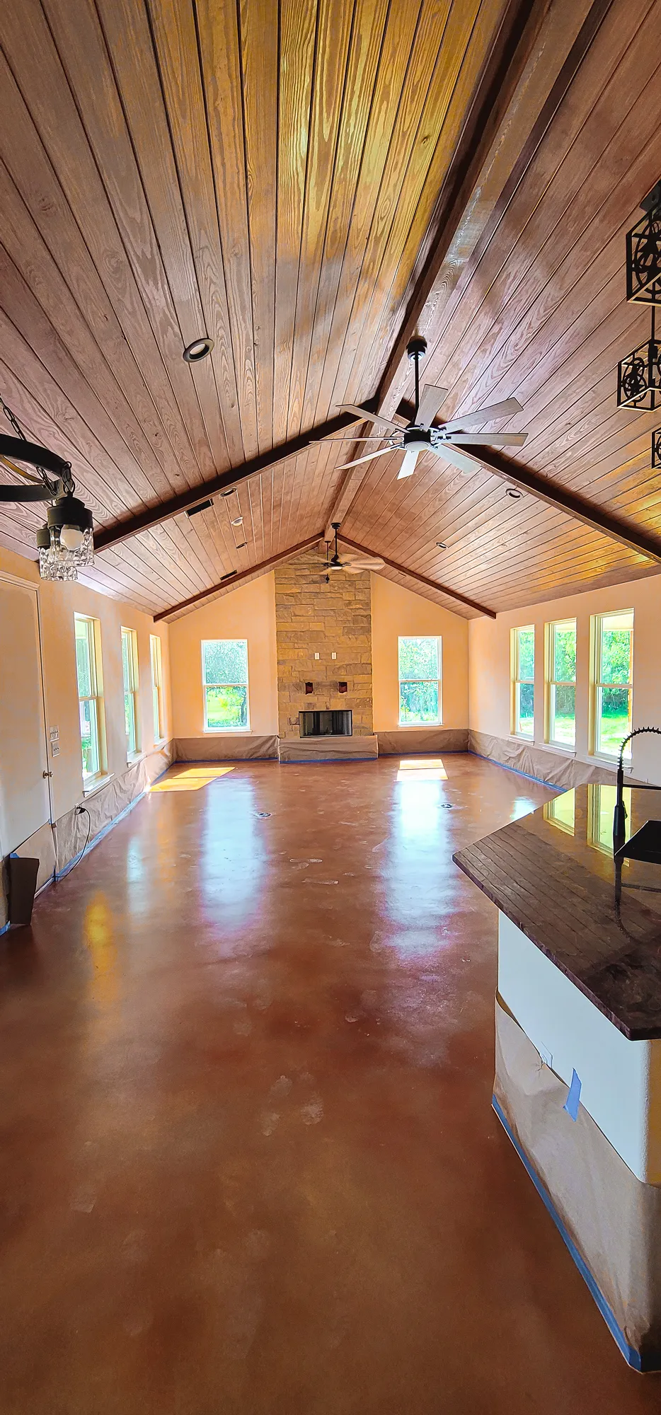 Residential open-concept space featuring resin-coated floors and exposed wood beams