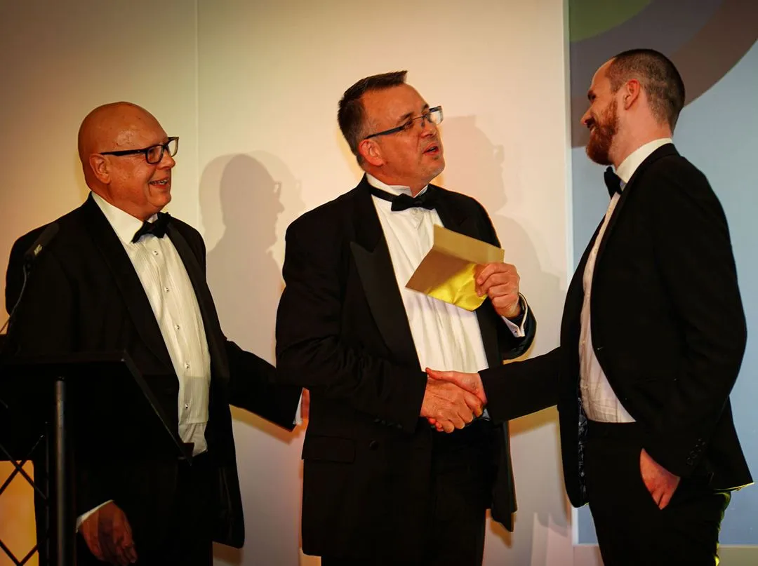 3 men in suits greeting eachother at an event