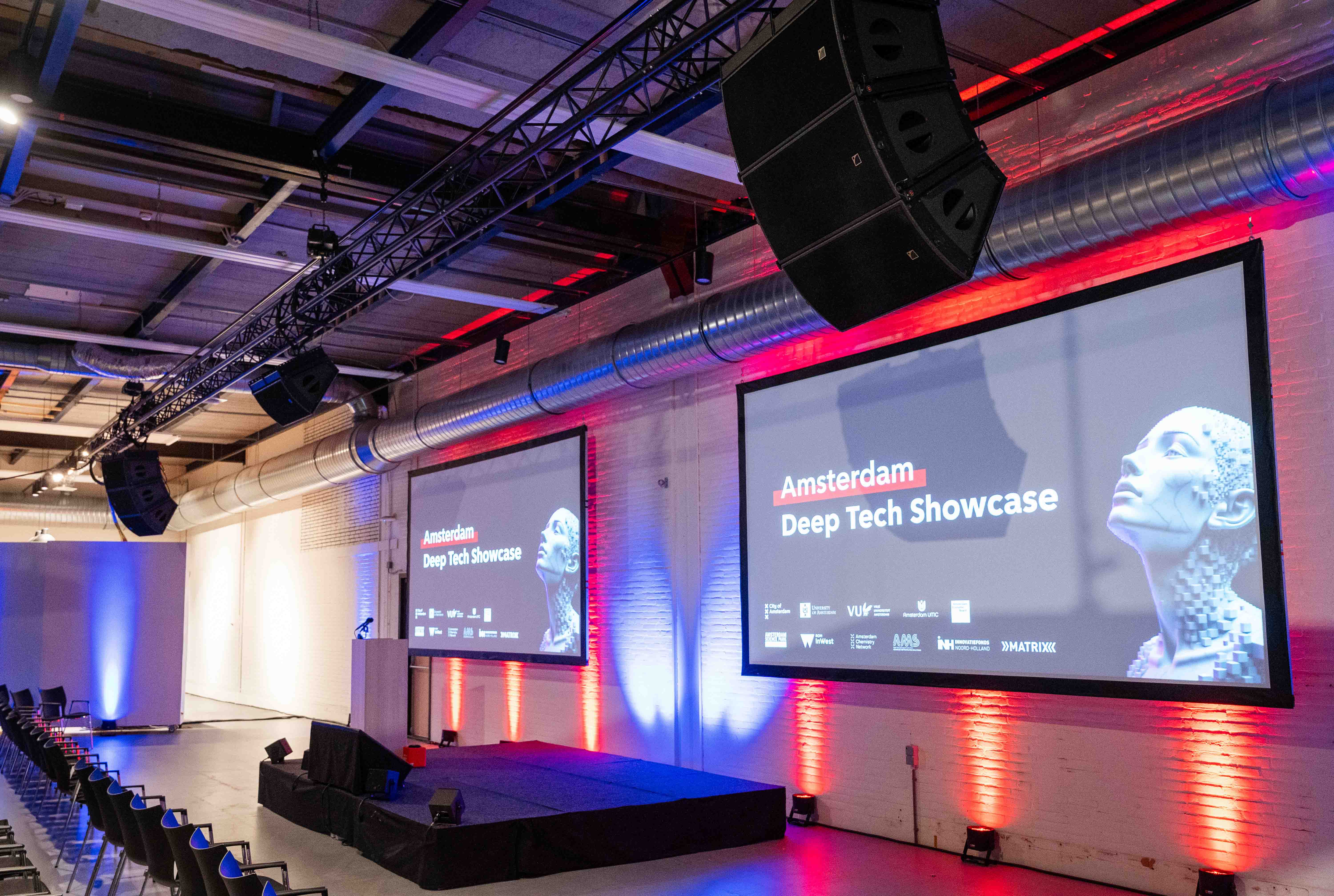 Hoofdpodium met twee ledschermen, L-Acoustics geluidstechniek en lichttechniek tijdens de Amsterdam Deep Tech Showcase